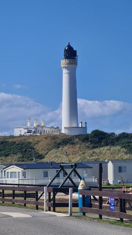 a lighthouse on a hill with a bench in front of it at Lyons Retreat in Lossiemouth
