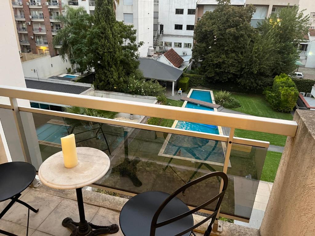 einen Balkon mit einem Tisch, Stühlen und einem Pool in der Unterkunft Departamento en Castelar in Castelar