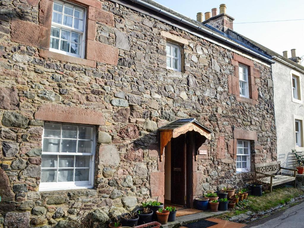 Willesdene Cottage في Abernethy: مبنى حجري قديم يوجد أمامه خزاف