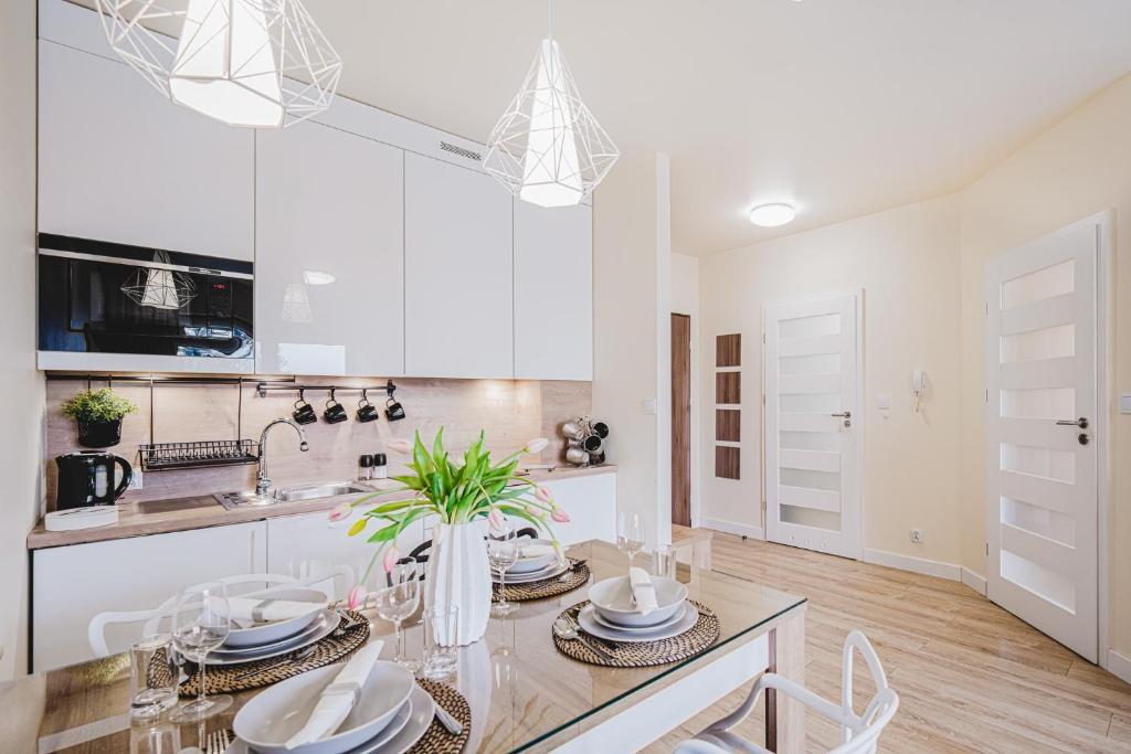 a white kitchen with a dining table and chairs at Apartament Niko in Toruń