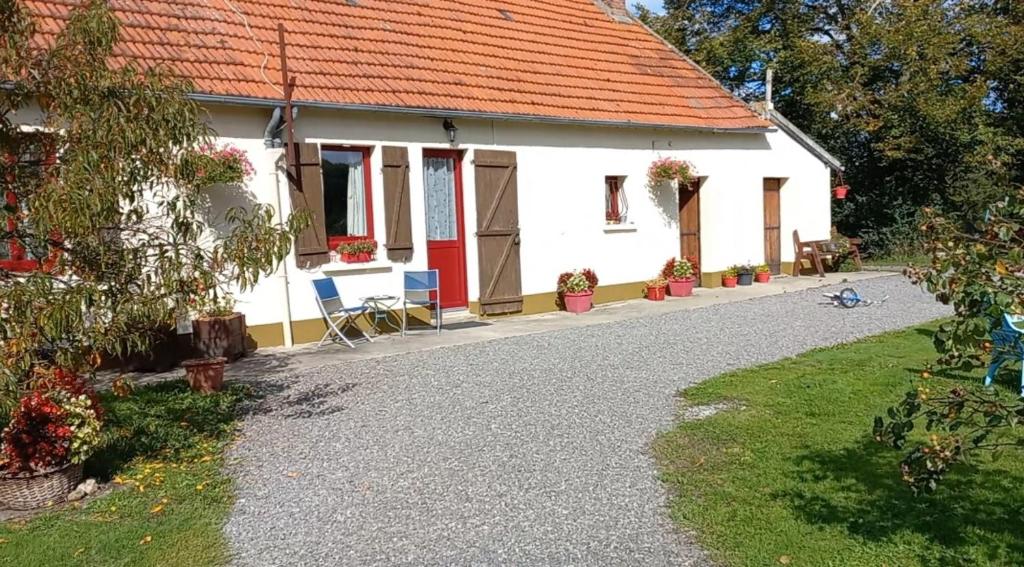 une maison blanche avec un toit rouge et une allée en gravier dans l'établissement Les Deux Sapins, à La Châtre-Langlin