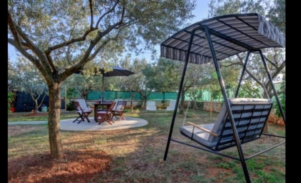 a swing set in a yard with a tree at MANDULERA in Peroj