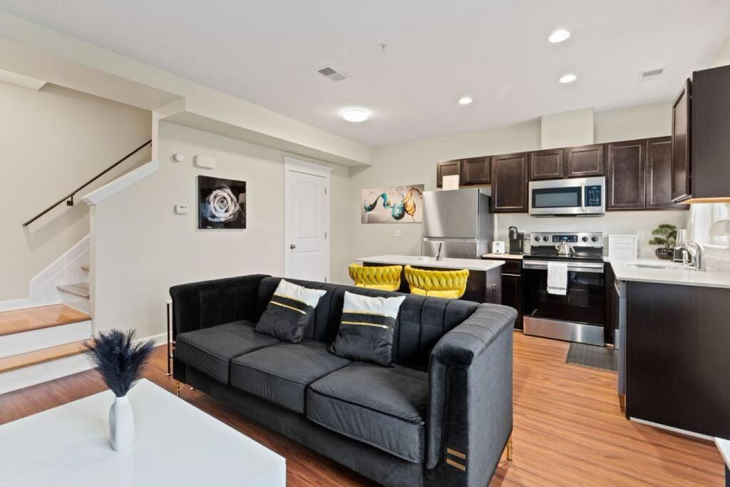 a living room with a black couch and a kitchen at Stylish and Comfortable 1-BR in the Heart of Detroit in Detroit