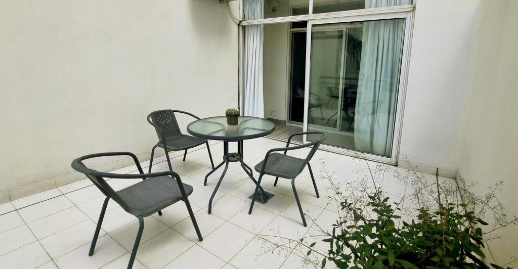 een glazen tafel en 4 stoelen op een balkon bij Departamento en Palermo in Buenos Aires