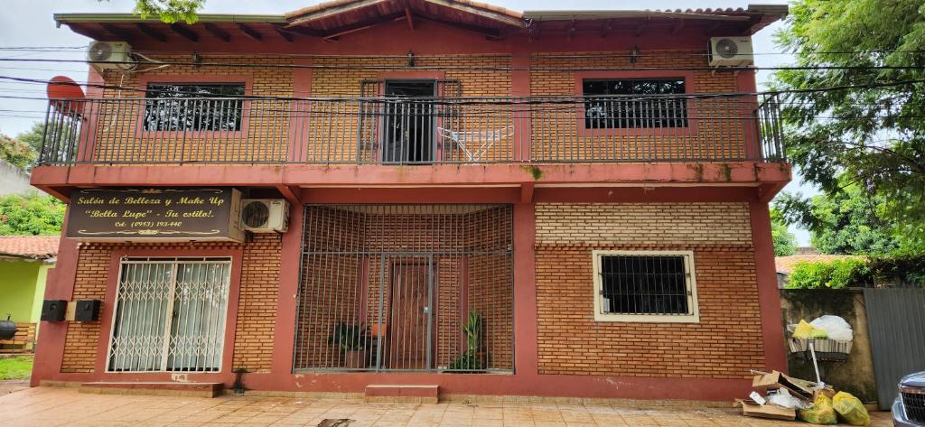 um edifício de tijolos vermelhos com uma varanda em Casa duplex en Área 4 CDE em Ciudad del Este