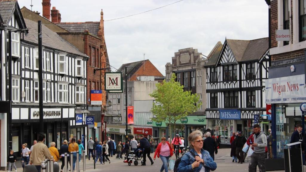 Un groupe de personnes marchant dans une rue urbaine animée dans l'établissement Private Room wigan, à Atherton