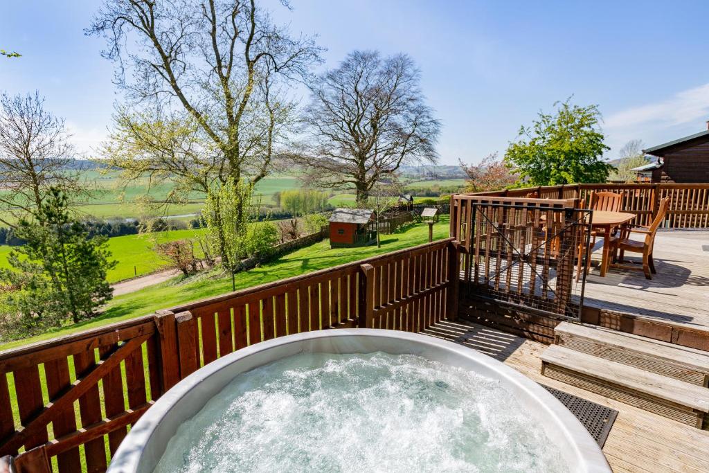 a hot tub on a wooden deck with a view at Mountain Ash Lodge with Hot Tub in Cupar