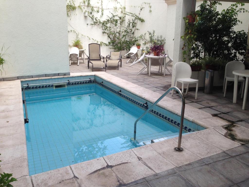 uma piscina com cadeiras e uma mesa e cadeiras em Cóndor Suites Apart Hotel em Mendoza