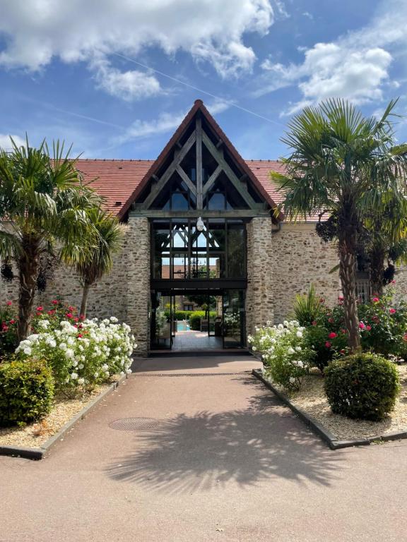 un bâtiment avec des palmiers et un sentier dans l'établissement Hotel Les Suites - Domaine de Crécy, à Crécy-la-Chapelle