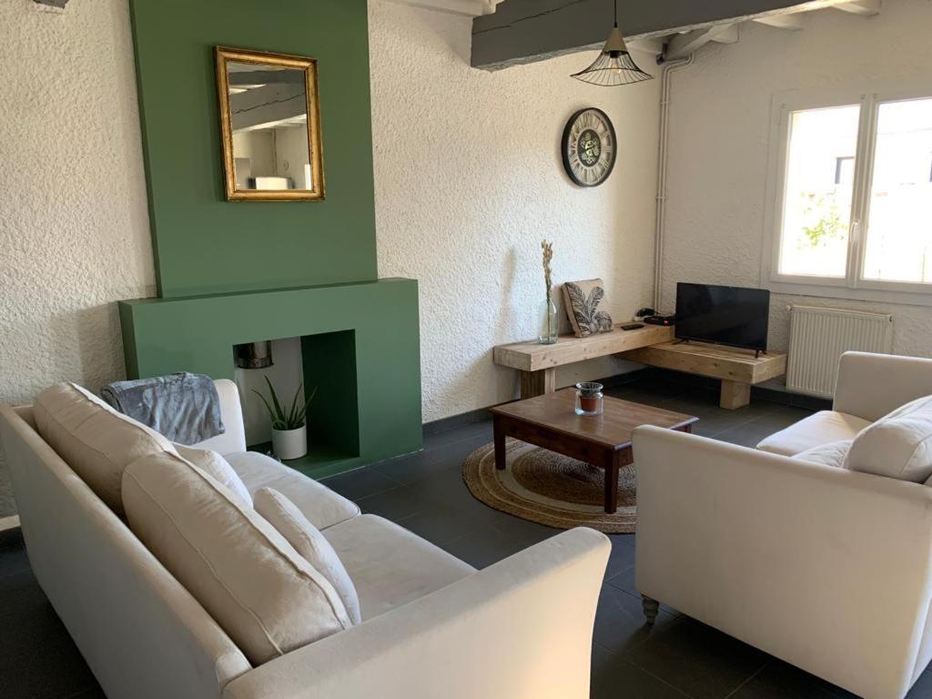 a living room with white furniture and a green wall at Maison de campagne chez Tatiana in Adé