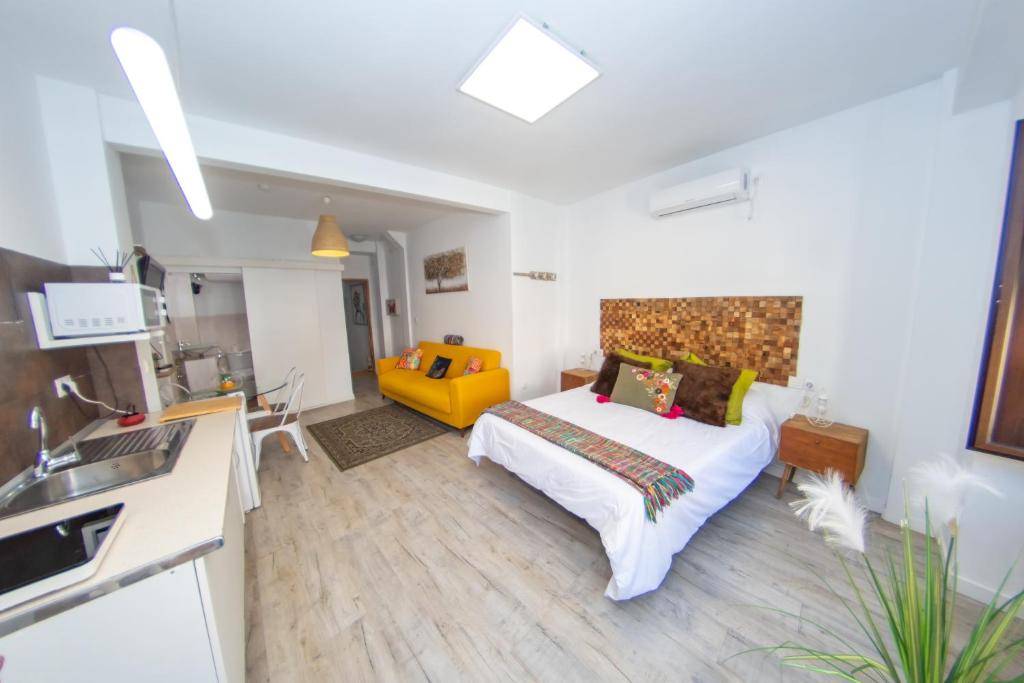 1 dormitorio con cama y sofá amarillo en UN SUEÑO EN SEVILLA, en Sevilla