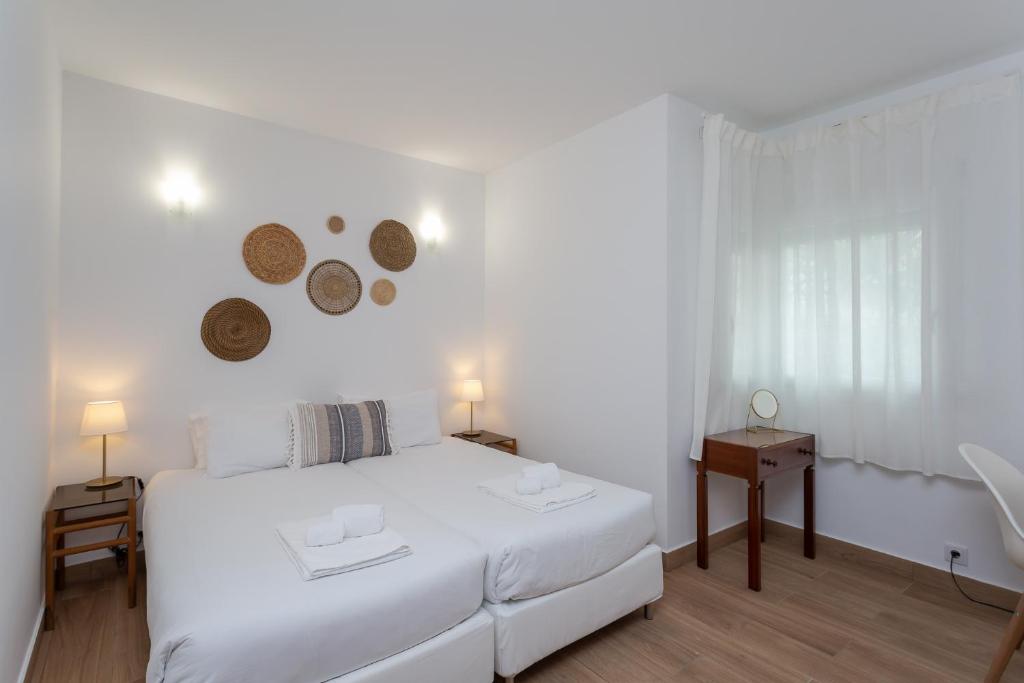 a white bedroom with a bed and a table at FishermenApartments - Carcavelos 1 in Carcavelos