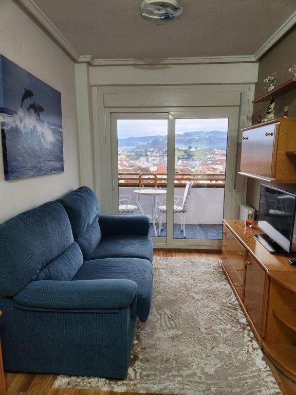 a living room with a blue couch and a large window at Estudio con vistas a la ciudad in Ourense