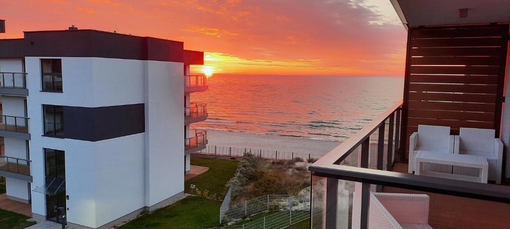 a sunset over the ocean from a balcony of a building at GARDENIA BLUE APART Dziwnów z widokiem na morze in Dziwnów