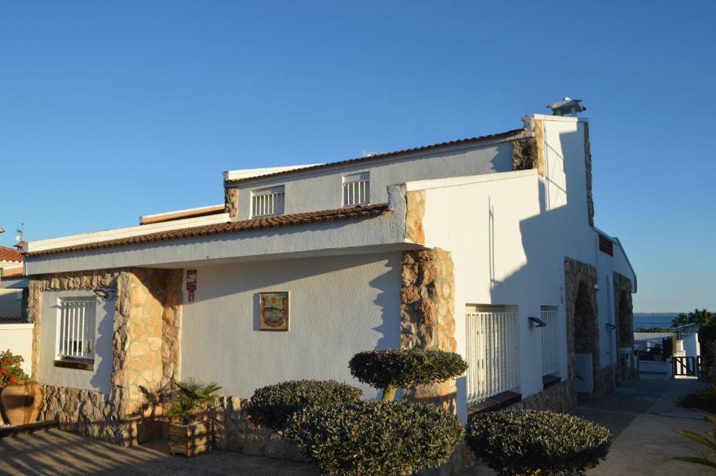 una casa blanca con arbustos delante en Casa Mar i Sol en L'Ampolla