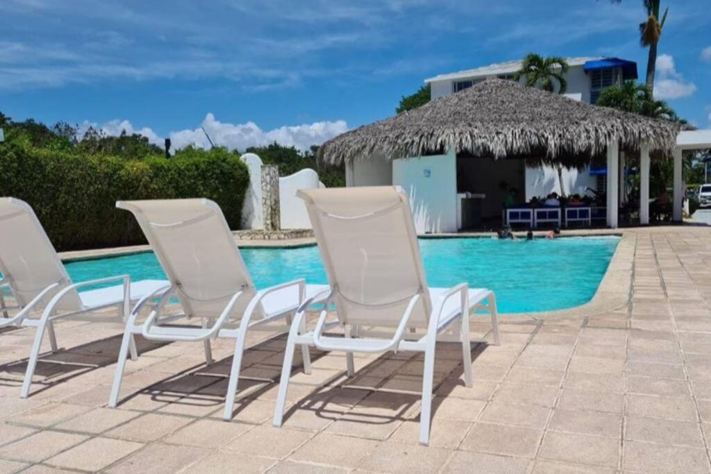 um grupo de cadeiras sentadas ao lado de uma piscina em Apartment with 2 bedrooms, swimming pool and beach em Juan Dolio