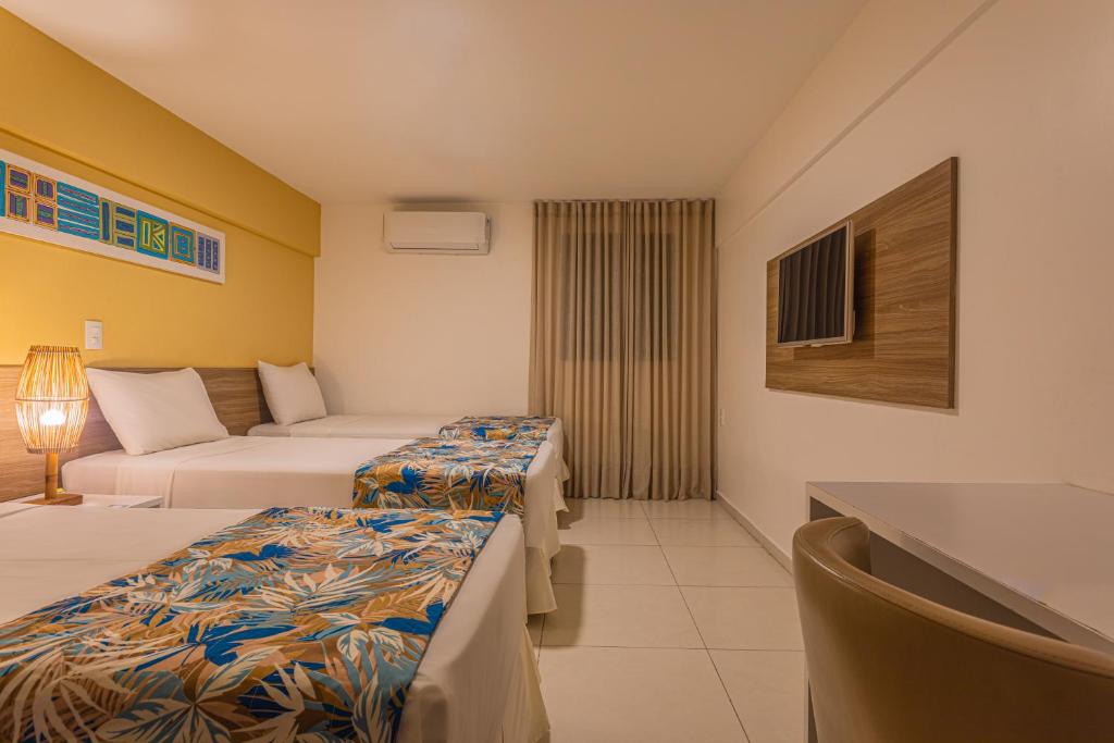 a hotel room with two beds and a couch at Slim Pajuçara by Tropicalis in Maceió