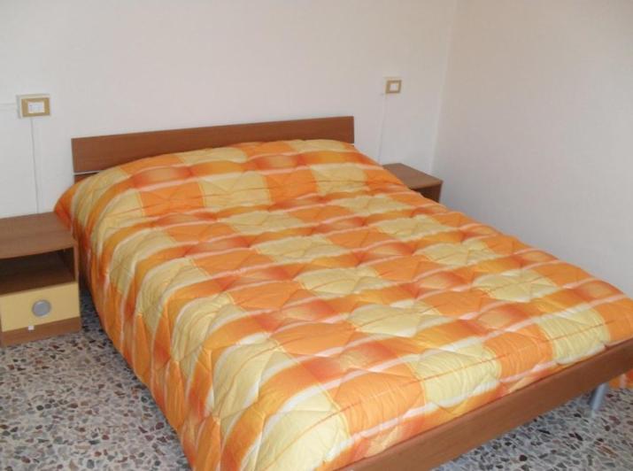 un letto con piumone arancione in una camera da letto di Borno B&B a Borno