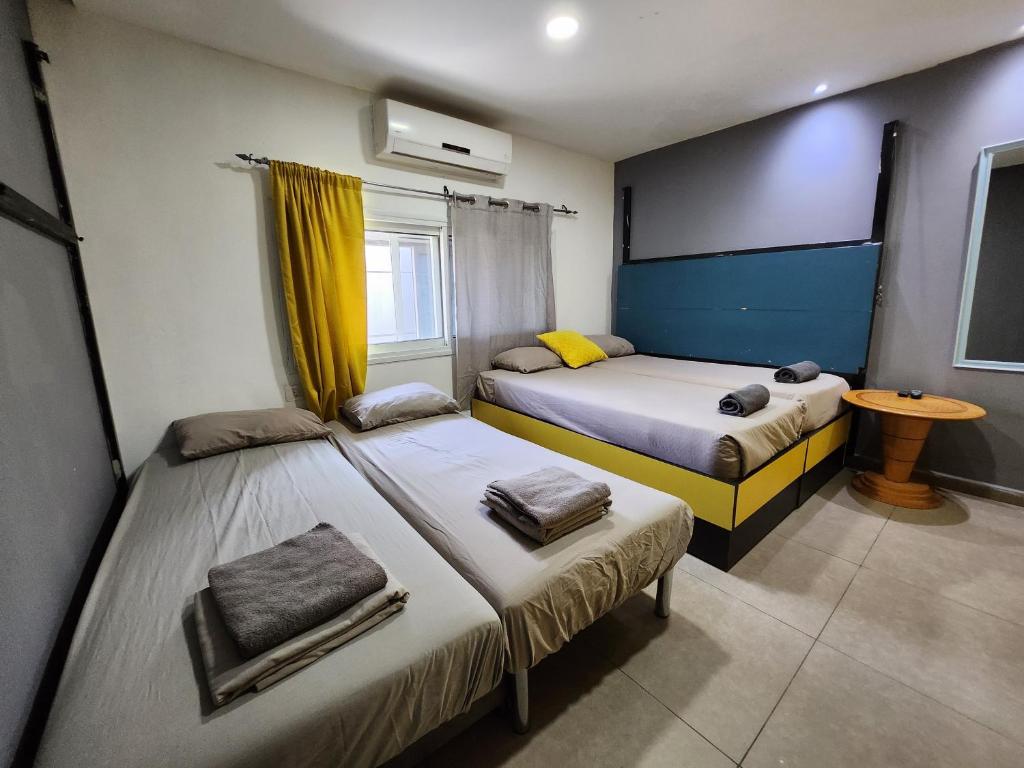a bedroom with two beds and a window and a table at Amdar Hostel in Eilat