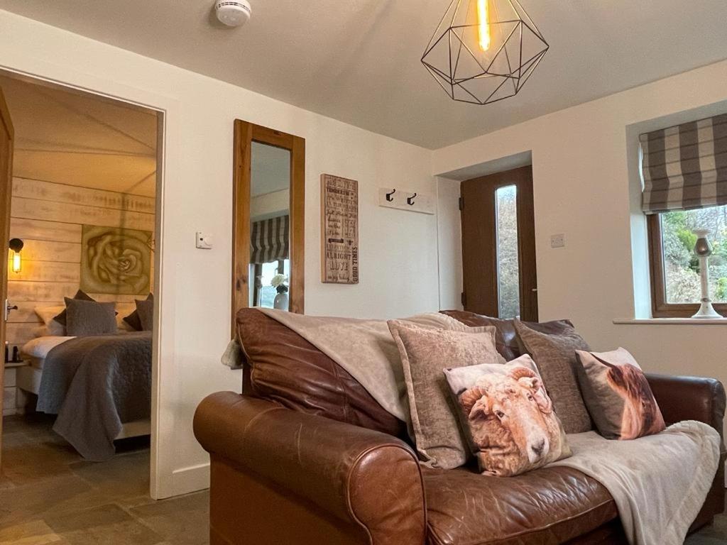 a living room with a leather couch and a bed at Hollies Cottage in Keighley