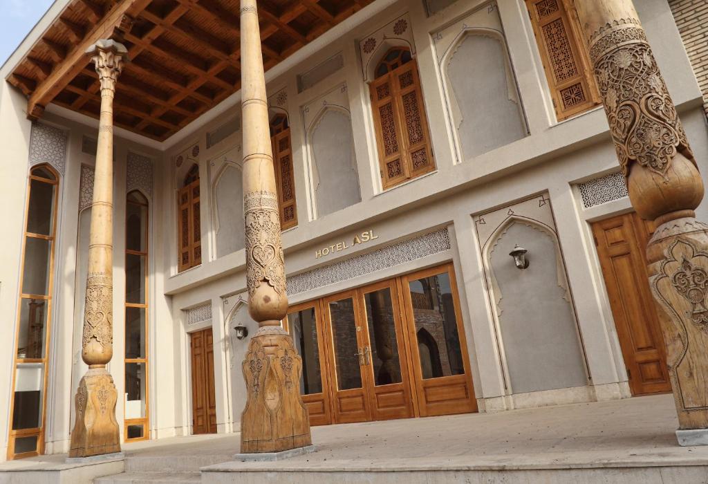 duży budynek z drewnianymi drzwiami i kolumnami w obiekcie Hotel ASL w mieście Buchara