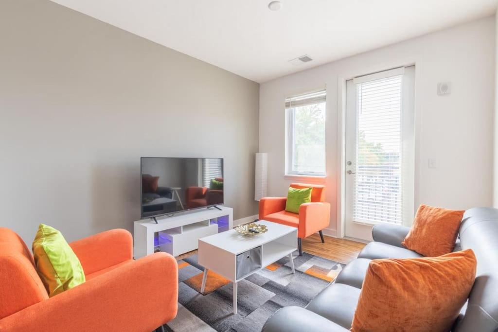 sala de estar con sillas de color naranja y TV en Affordable 1BD, Comfy Queen Beds, with GYM en Indianápolis