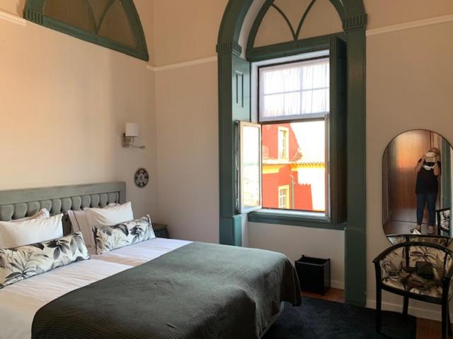 a bedroom with a large bed and a window at Ilha 12 Suites in Coimbra