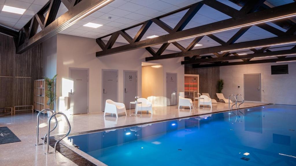 a large swimming pool with white chairs and a table at Paradis på Sørlandet in Kristiansand