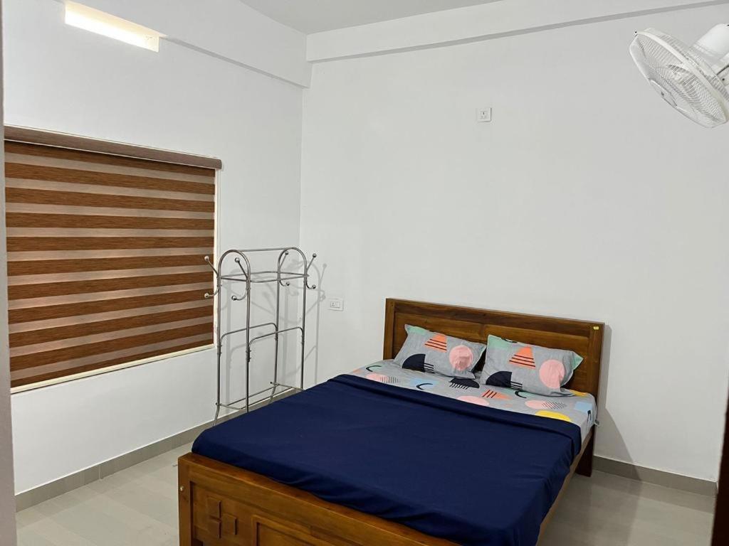 a bedroom with a bed with blue sheets and pink pillows at Wayanad Biriyomz Residency, Kalpatta, Low Cost Rooms and Deluxe Apartment in Kalpetta