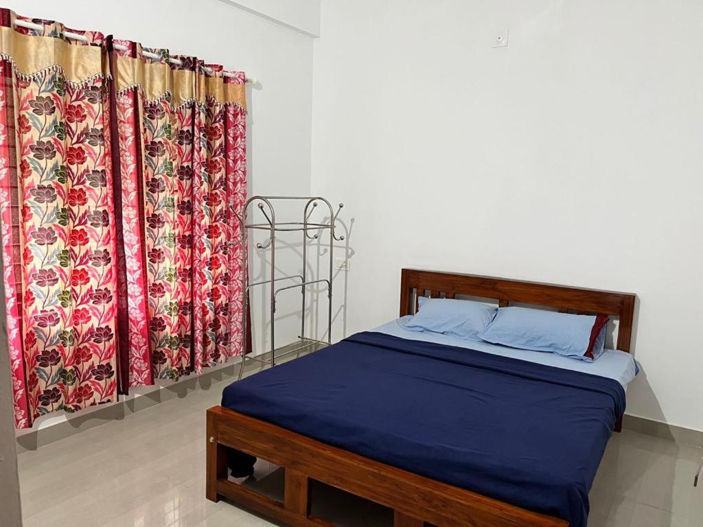 a bedroom with a bed and two curtains at Wayanad Biriyomz Residency, Kalpatta, Low Cost Rooms and Deluxe Apartment in Kalpetta