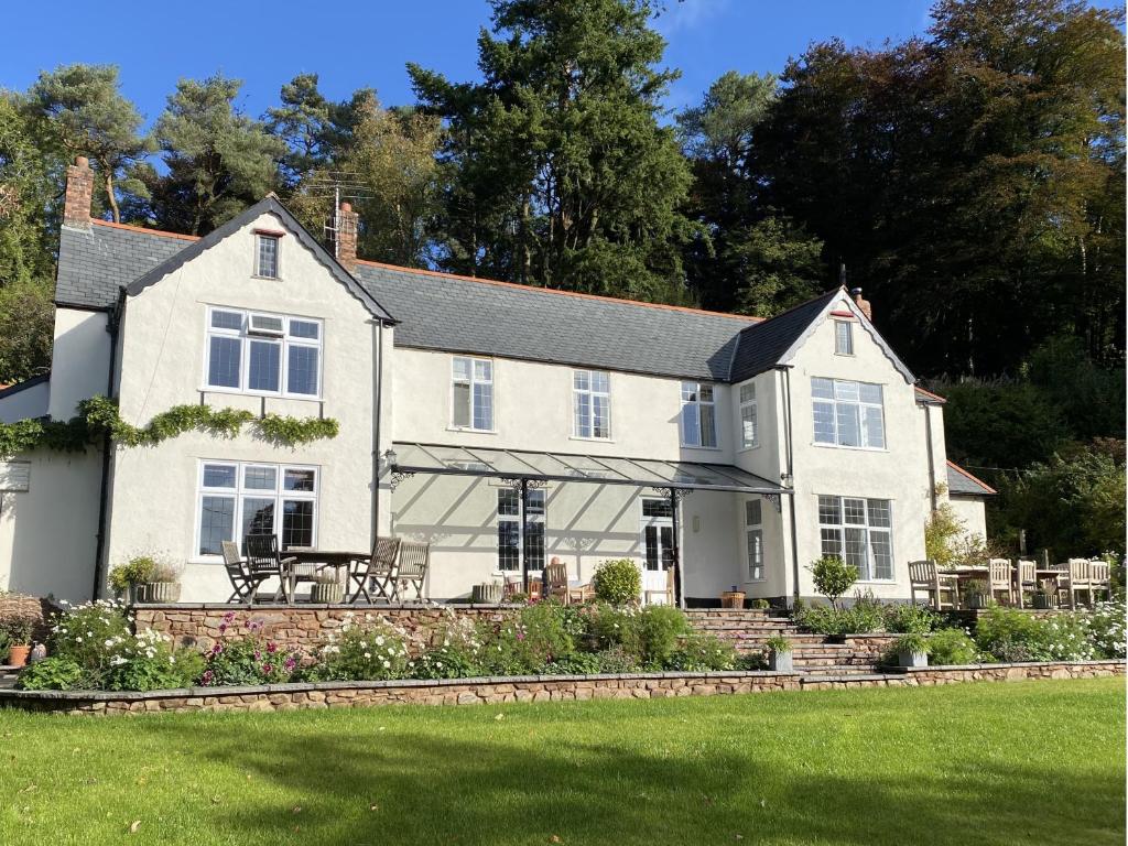 ein weißes Haus mit einem Picknicktisch im Vorgarten in der Unterkunft Edgcott House in Exford