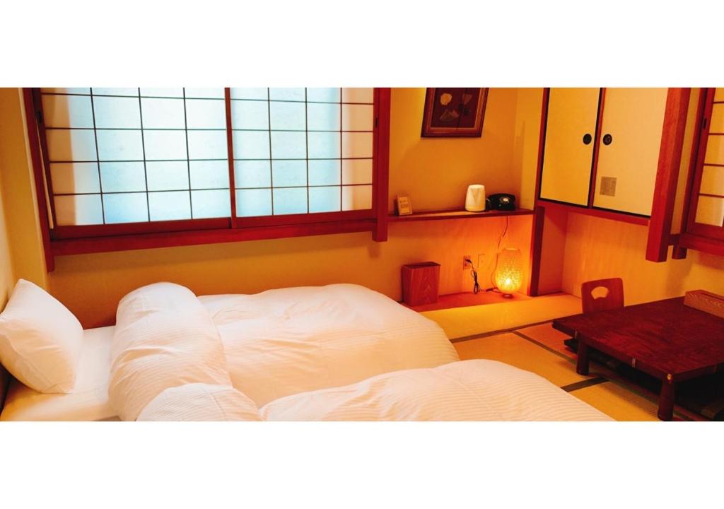 Habitación con cama blanca, mesa y ventanas. en Nara Ryokan - Vacation STAY 49560v en Nara