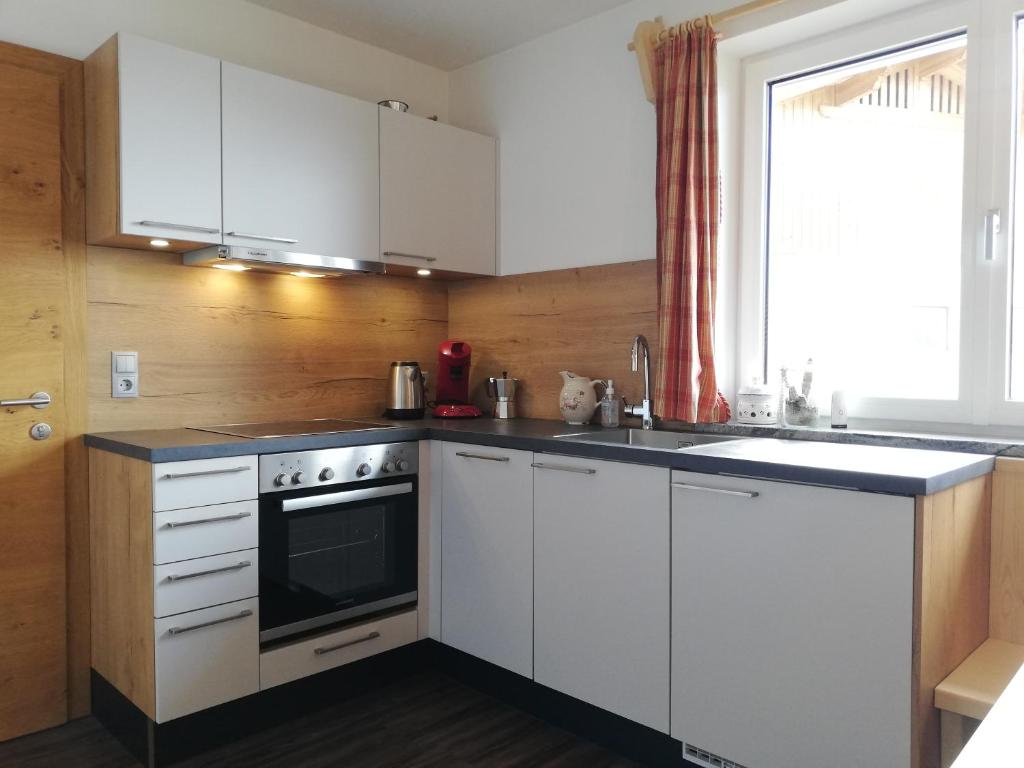 a kitchen with white cabinets and a stove and a window at Much`s Bergstüberl in Wattenberg