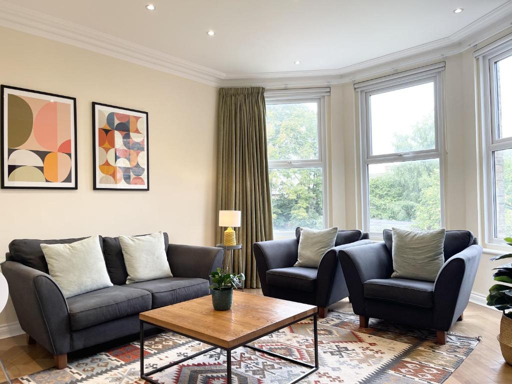 ein Wohnzimmer mit Sofas, einem Tisch und Fenstern in der Unterkunft Glenlyn Hotel & Apartments in Barnet