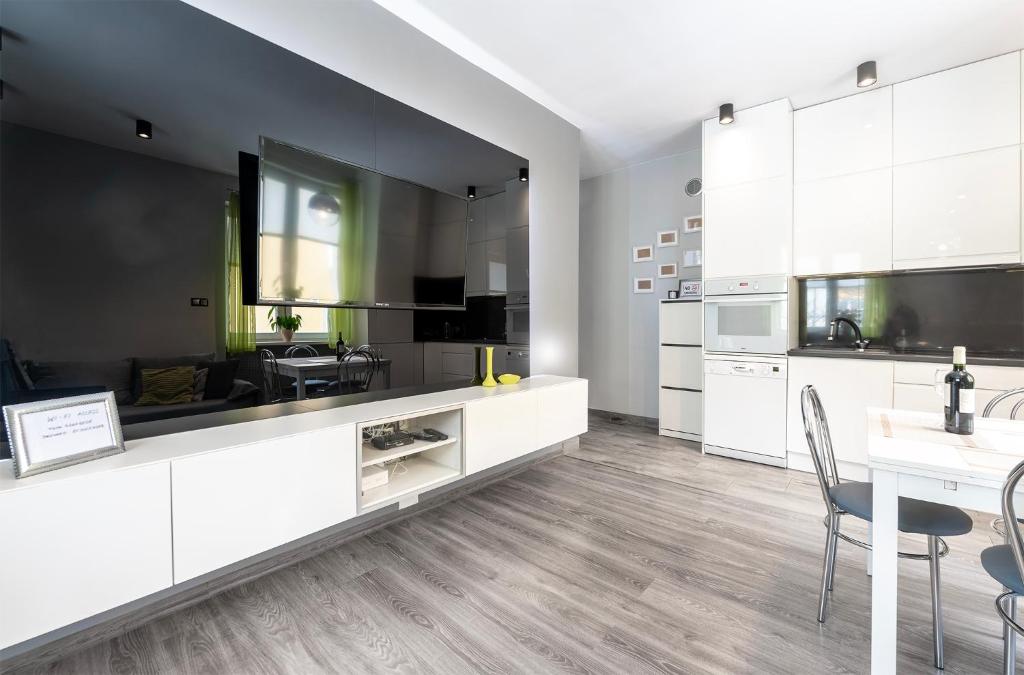 a kitchen with white cabinets and a dining table at HILLWOOD Apartment in Łódź