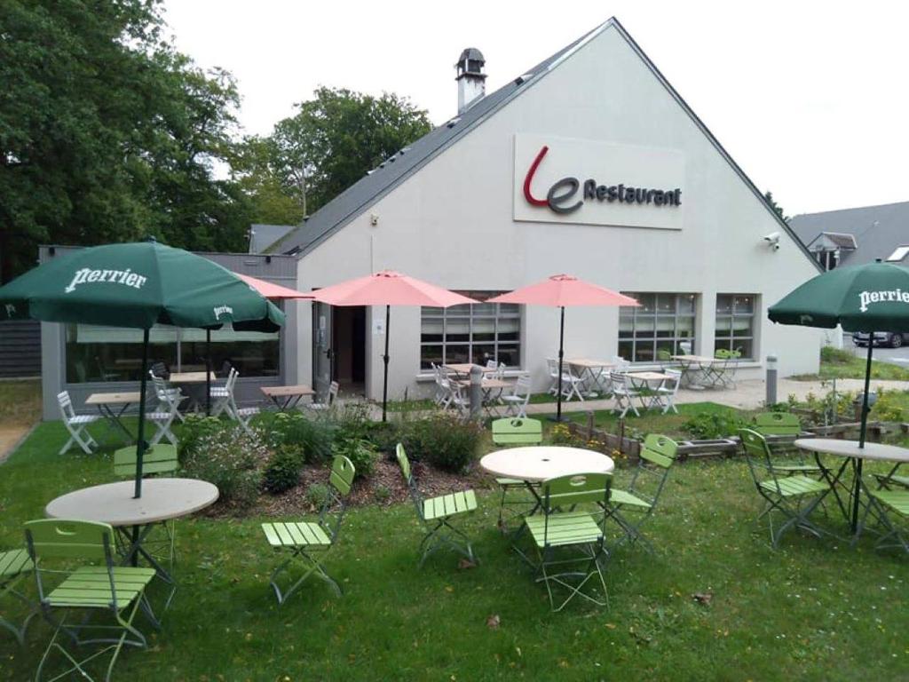 a group of tables and chairs with umbrellas in front of a building at Campanile Hotel Compiegne in Compiègne