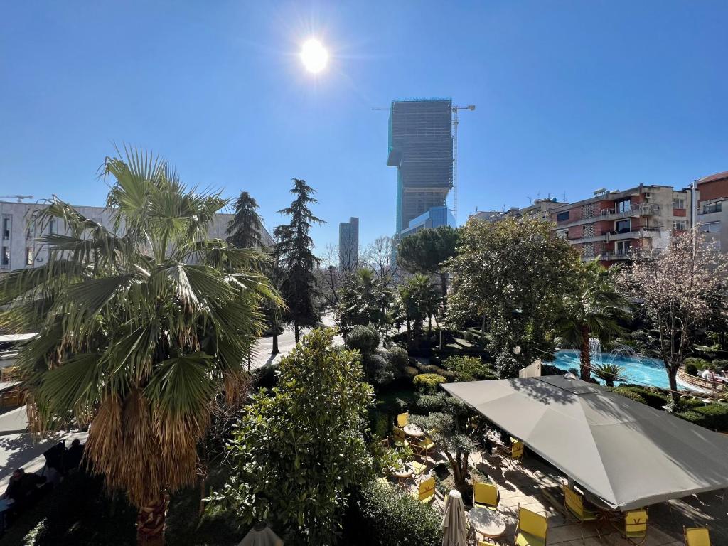 Blick auf einen Park mit Bäumen und ein Gebäude in der Unterkunft Apartment in Skanderbeg Square - Tirana Center 1 in Tirana