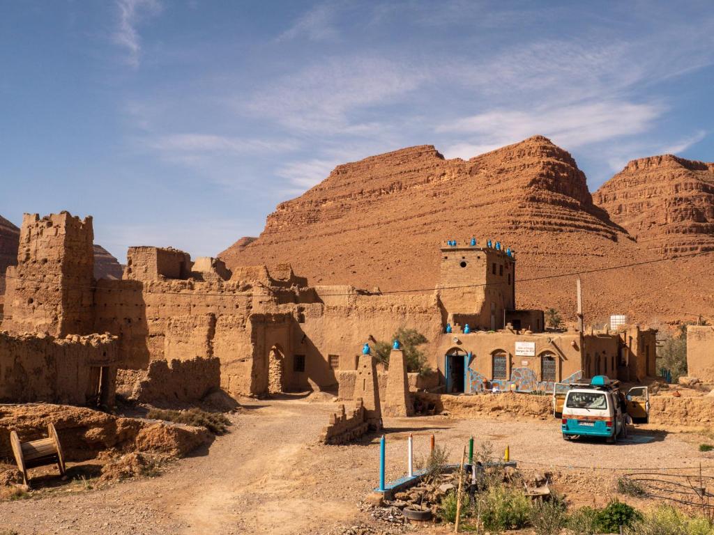 une camionnette garée devant un bâtiment dans le désert dans l'établissement Chambres dans casbah - Gite D'étape Gorges De Ziz, à Errachidia