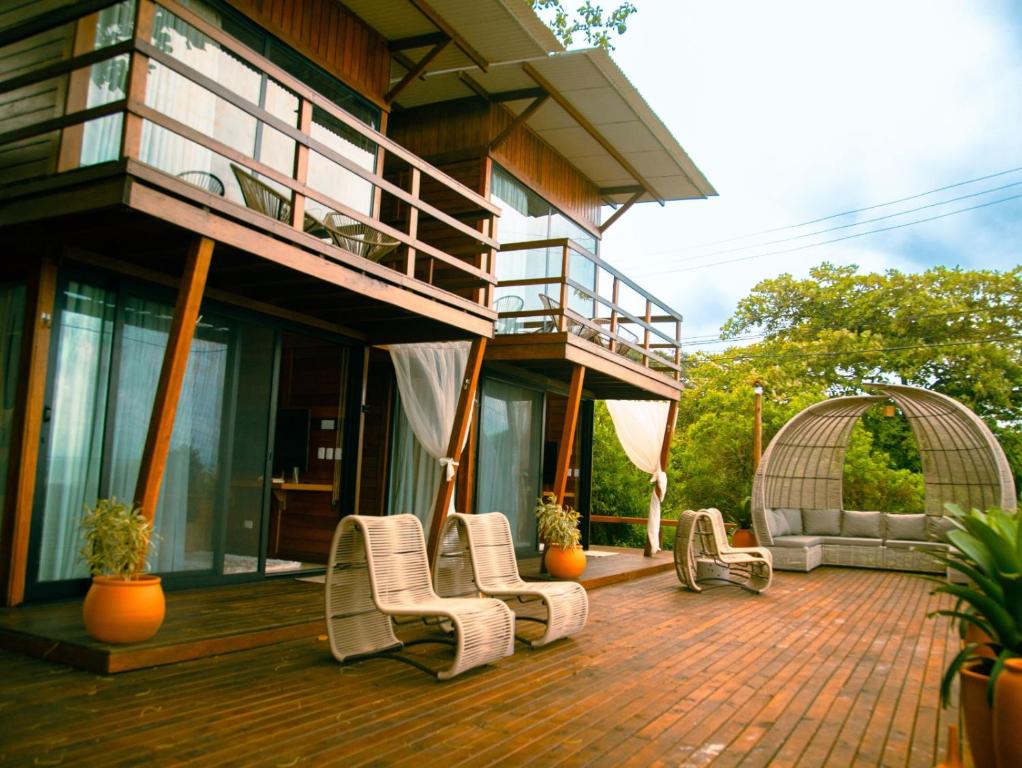 a house with a deck with chairs and a balcony at Ilha do Mel Lodges in Ilha do Mel