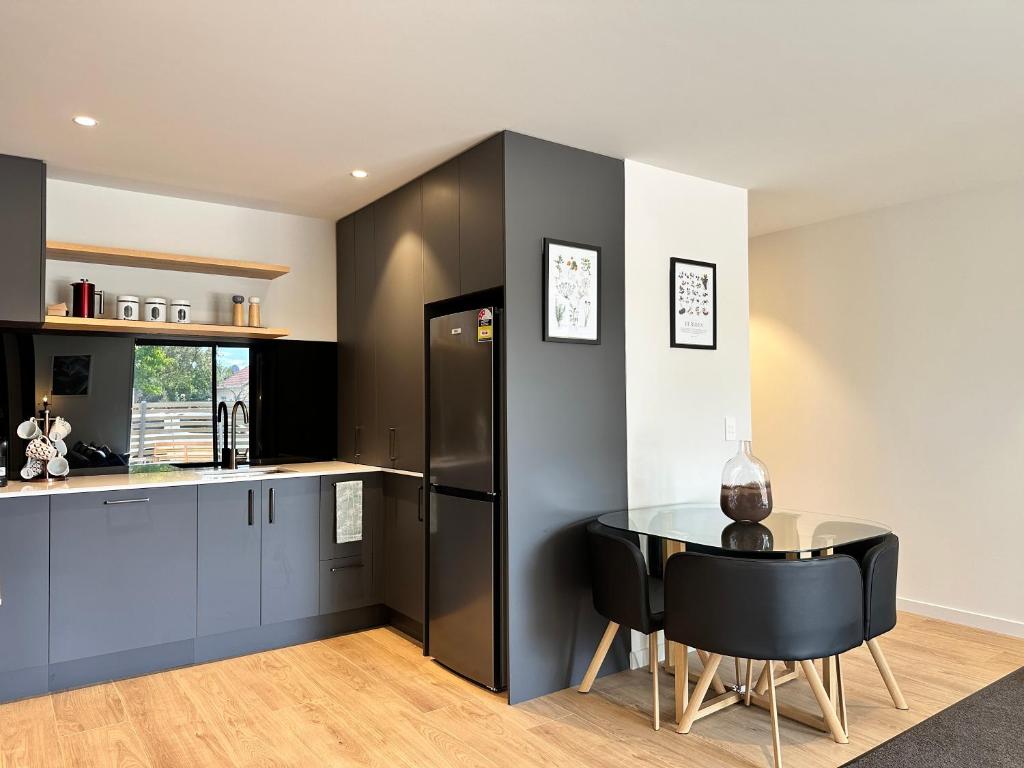 a kitchen with a black refrigerator and a table at Gem in Papanui Christchurch in Christchurch