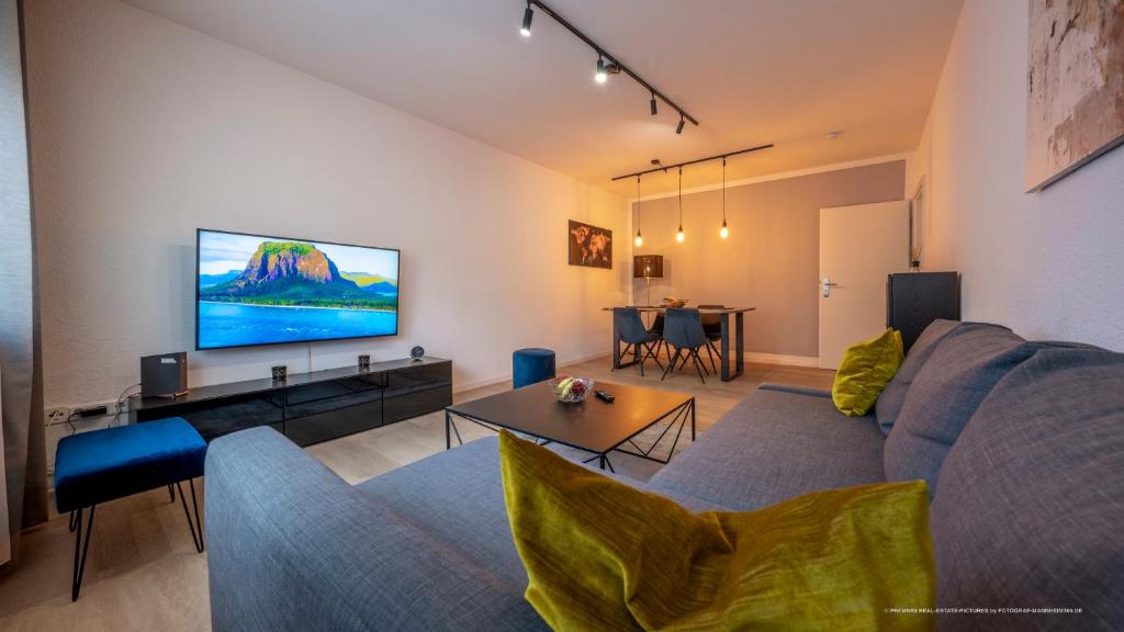 a living room with a blue couch and a flat screen tv at FLAIR: stylisches Apartment - Netflix - BASF - Uni Mannheim in Ludwigshafen am Rhein