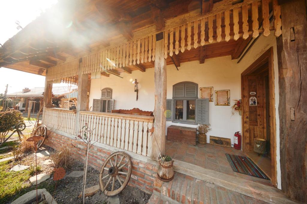 a house with a wooden porch with a wooden wheel at Slovenska Koliba 194 in Mădăraş