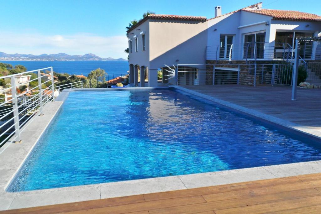 une piscine avec de l'eau bleue devant une maison dans l'établissement Maurin 3405 villa, aux Issambres