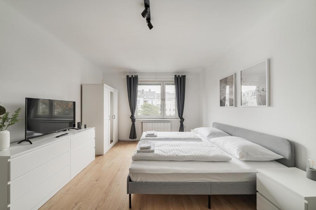 een witte slaapkamer met een bed en een televisie bij Homely apartment - 10 minutes to Stephansplatz in Wenen