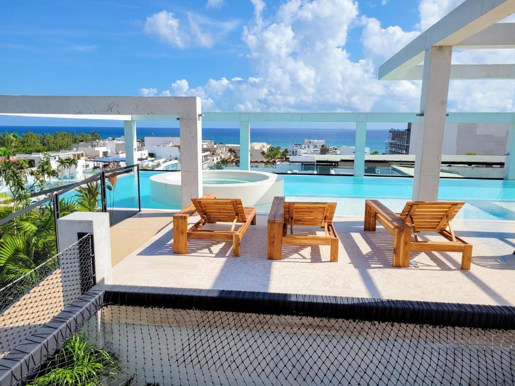un balcón con 2 sillas y una piscina en Ceren Luxury Apartments at Fifth Avenue by Spot Rentals en Playa del Carmen
