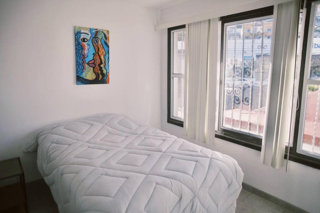 a white bed in a room with two windows at Casa Macfarland Boutique in Ensenada