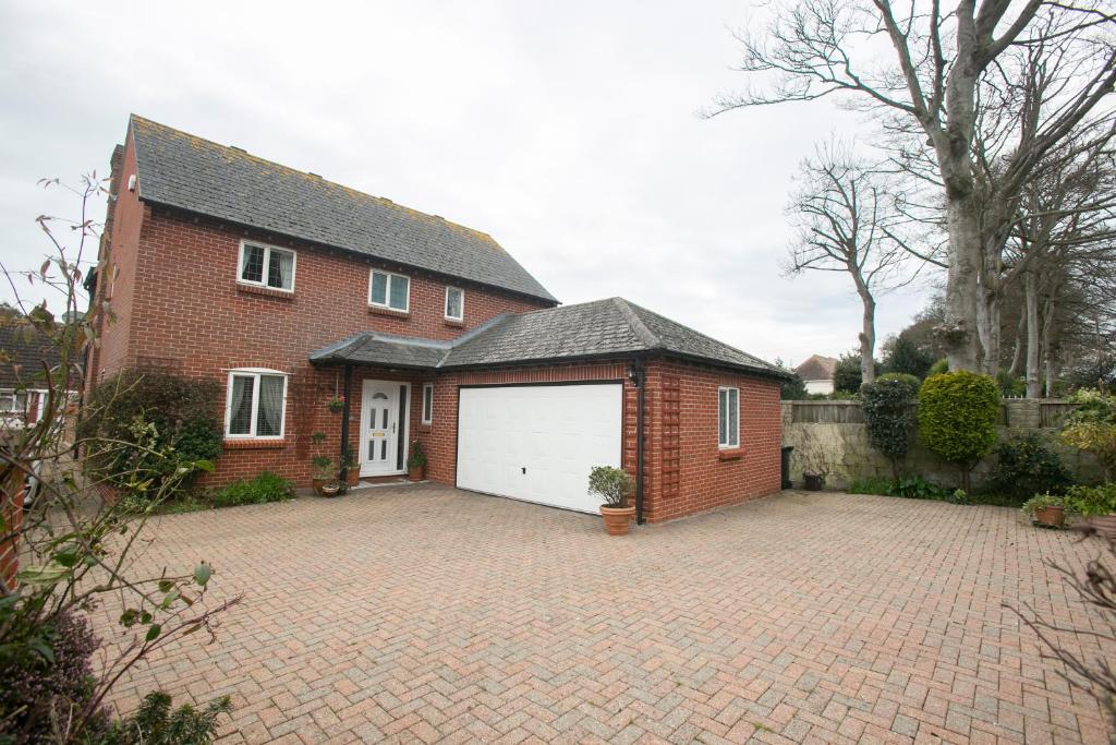 a red brick house with a white garage at Oceanside in Wyke Regis
