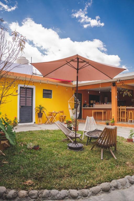 a yellow house with two chairs and an umbrella at Casa Sofia Guest House in San Cristóbal de Las Casas