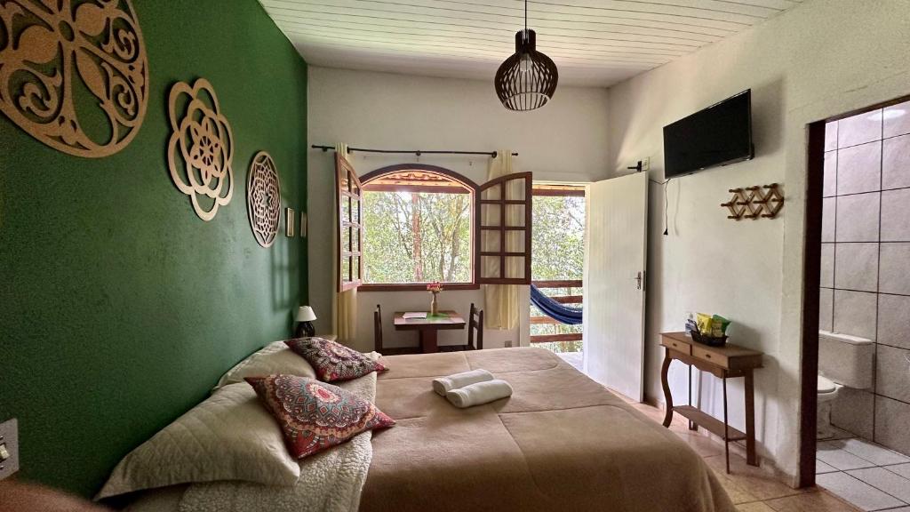 a bedroom with a green wall with a bed at Sensorial Macacos in Macacos