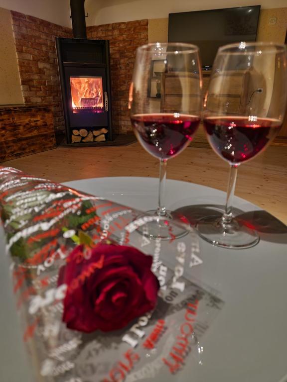 deux verres de vin rouge et une rose sur une table dans l'établissement Juliana House, 